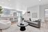 Modern open-concept living area featuring a stylish kitchen with a breakfast bar, cozy seating, and elegant decor in a bright apartment setting.