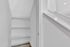Bright, modern closet nook with sleek white shelving and elegant wood flooring, perfect for stylish storage solutions.
