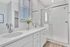 Bright modern bathroom with elegant double sinks, sleek fixtures, and a spacious glass shower.