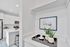 Modern kitchen with elegant white cabinetry and sleek appliances, complemented by stylish decor and vibrant potted plants, exuding a serene and inviting atmosphere.