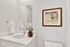 Elegant bathroom with a modern sink, large mirror, and tasteful artwork, creating a serene and stylish ambiance.