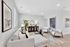 Modern living room with elegant white sofa, contemporary chairs, stylish artwork, and lush greenery, beautifully accented by soft lighting.
