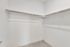 Spacious walk-in closet with sleek white walls and modern shelving, ready to enhance your storage solutions.