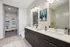 Elegant bathroom featuring a double vanity with sleek countertops, modern fixtures, and an artistic wall painting, complemented by a spacious walk-in closet with organized shelving.