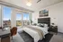 Modern bedroom interior with expansive floor-to-ceiling windows, lush cityscape views, elegant furnishings, and stylish decor.