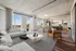 Bright and modern open-concept apartment featuring a luxurious living area with floor-to-ceiling windows, elegant furnishings, and a stylish kitchen with dining space.