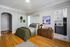 Charming and cozy bedroom with hardwood flooring, modern decor, and adjacent view into a sleek kitchen. Ideal for comfortable living.