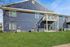 Modern blue apartment building with spacious balcony and lush green lawn, perfect for enjoying outdoor living.