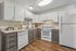 Sleek modern kitchen with white cabinetry, stainless steel appliances, and elegant wood flooring, offering a bright and inviting space.