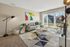 Bright and inviting living room with modern decor, featuring a cozy gray sofa, abstract wall art, and large sliding glass doors letting in natural light.