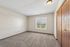 Bright and airy bedroom with plush carpet, large window offering scenic views, and wooden closet doors.