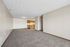 Spacious open-plan living area with cozy carpet flooring and a modern kitchen featuring wooden cabinetry.