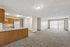 Spacious open-plan living area featuring a modern kitchen with wooden cabinets and a bright living room with sliding glass doors.