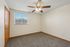 Bright, pristine bedroom with light beige walls and cozy carpet, featuring a stylish ceiling fan and ample natural light from the window.