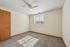 Bright and inviting bedroom with soft carpet flooring, large sunlit window, and elegant ceiling fan, perfect for relaxation.