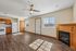 Bright and spacious living area with elegant wood flooring, featuring a cozy fireplace, modern ceiling fan, and ample natural light from large windows. Stylish kitchen area with wooden cabinetry and essential appliances.