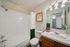 Elegant bathroom featuring a pristine white tub, modern fixtures, and tasteful decor with warm wooden accents and ambient lighting.