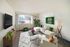 Bright and modern living room with large window, cozy sectional sofa, and stylish decor in a serene apartment setting.