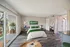 Bright and modern bedroom featuring elegant decor, sleek wood flooring, and a spacious window opening to a scenic balcony view.