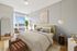 Bright and elegant bedroom showcasing a cozy queen bed, stylish decor, and large window with natural light.