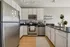 Modern kitchen with sleek stainless steel appliances, white cabinetry, and elegant black countertops. Bright and inviting space with natural wood flooring and contemporary lighting.