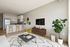 Modern living room featuring a sleek kitchen with island and barstools, stylish decor, hardwood floors, and vibrant greenery.