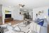 Bright and modern living room with open kitchen, stylish decor, and natural light streaming through the windows.