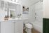 Elegant bathroom with modern fixtures, pristine white cabinetry, and a serene ambiance, featuring decorative plants and stylish toiletries.