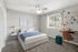 Bright and inviting bedroom featuring cozy decor, a comfortable bed with blue accents, modern artwork, and ample natural light from a large window.