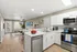 Modern open-concept kitchen and living room with sleek stainless steel appliances, bright white cabinetry, and cozy seating area.