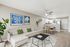 Modern living room with elegant decor, featuring a cozy beige sofa, stylish wall art, and a seamless transition to the open kitchen and dining area.