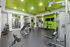 Vibrant apartment gym featuring state-of-the-art Cybex equipment, stylish green accents, and full-length mirrors.