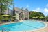 Inviting poolside escape with modern sun loungers and vibrant green umbrellas at a stylish apartment complex.