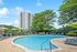 Inviting outdoor pool area with vibrant green umbrellas and comfortable lounge chairs, perfect for relaxation amidst a lush landscape and modern apartment backdrop.