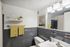 Bright and modern bathroom featuring chic gray tiles, vibrant yellow patterned towels, and elegant wall decor.