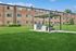 Inviting apartment community with lush green lawns and a modern outdoor grilling area under a stylish pergola.