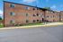 Charming brick apartment building with well-maintained landscaping and large windows under a clear blue sky.