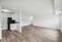 Bright open-plan living area with sleek wood flooring and modern kitchen in a contemporary apartment.