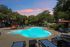 Inviting outdoor pool area with stylish lounge chairs, lush greenery, and a vibrant sunset backdrop.
