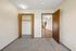 Inviting bedroom with soft carpet, ample closet space, and warm wood accents, offering a peek into the spacious living area beyond.