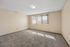 Bright, spacious room featuring plush carpeting and a large window with vertical blinds, creating an inviting atmosphere.