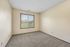 Bright and inviting bedroom with plush carpeting and a large window offering serene outdoor views.