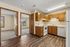Cozy apartment featuring a warm-toned kitchen with wooden cabinets, inviting natural light, and two spacious bedrooms visible through open doorways.