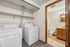 Modern laundry area with washer and dryer adjacent to a bright bathroom, offering convenience and style.