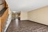 Modern apartment interior with sleek wooden flooring, open layout, and cozy carpeted staircase leading upstairs.