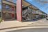 Modern two-story apartment building with striking red doors, sleek metal railings, and a well-maintained exterior under a clear blue sky.
