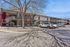 Charming two-story apartment complex with vibrant red doors, ample parking space, and serene trees casting shadows on a sunny day.