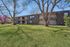Charming apartment building with spacious balconies surrounded by lush greenery and vibrant spring trees.