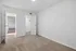 Bright and spacious bedroom with plush carpet flooring, featuring a modern walk-in closet and open doorway leading to a wooden floored hallway.