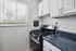 Bright, modern kitchen with sleek white cabinets, stainless steel gas stove, and blue marble-style countertop under natural light.
